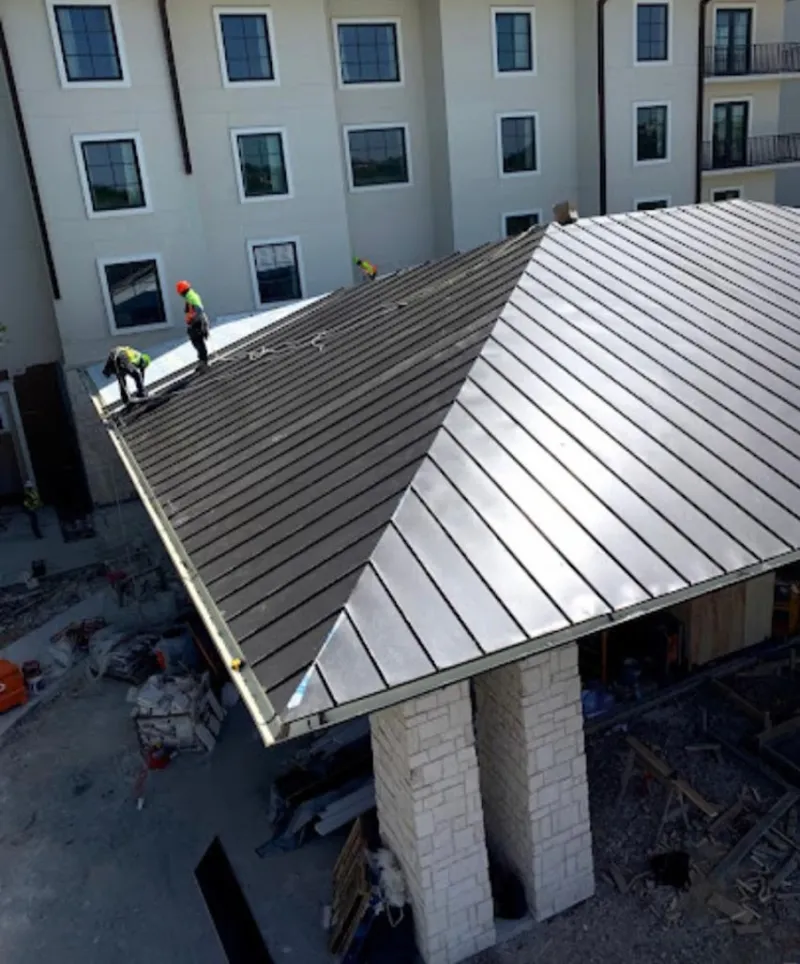 Crew installing standing seam metal roof panels on a commercial project in Lincoln